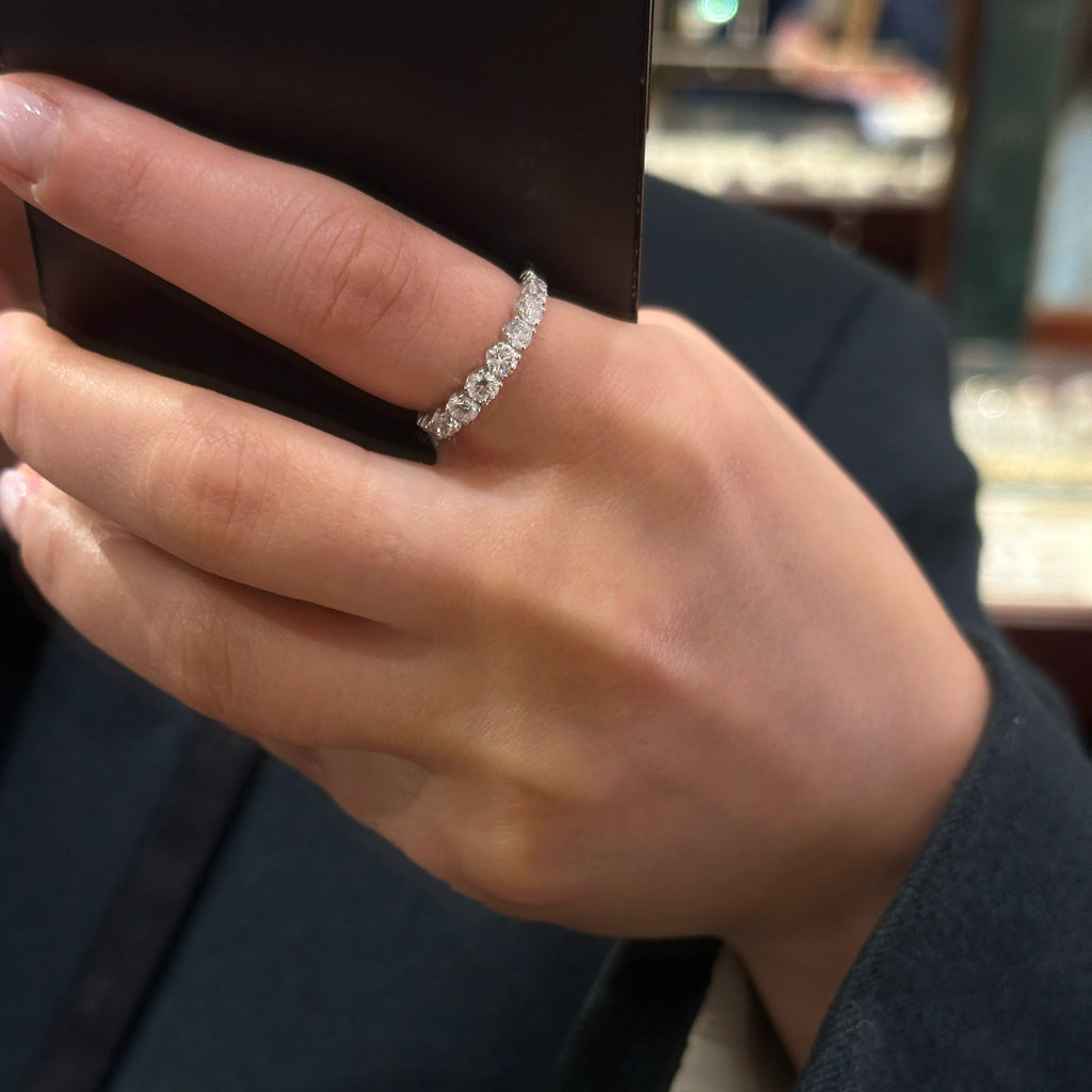A close-up of a person's hand wearing an 18k white gold band ring with 15 diamonds for a total carat of 1.45ct.
