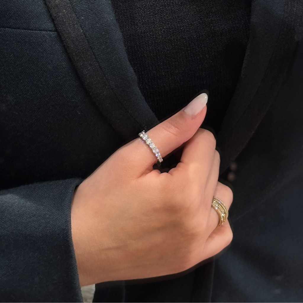 Close-up of a person wearing several rings, including the 15 diamonds riviera ring in white gold with 1.45ct of natural diamonds.