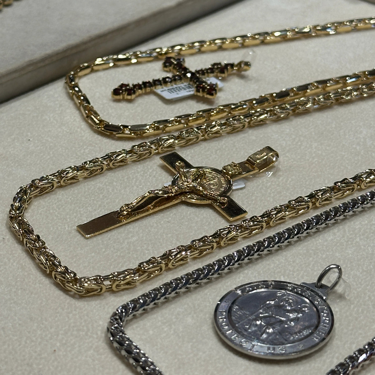 A close-up display of several jewelry pieces, including yellow and white gold chains and crosses.