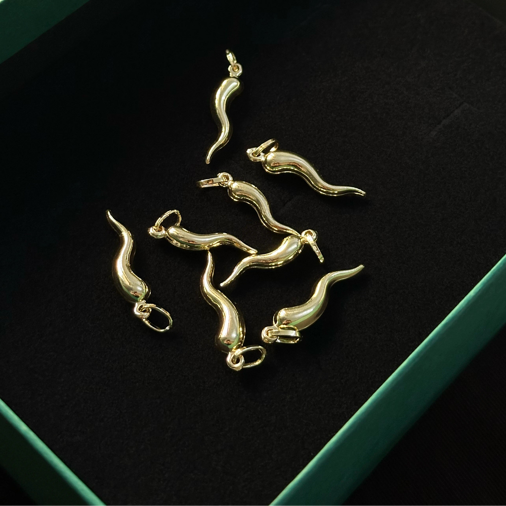 Eight Italian Gold Lucky Horn Charms, arranged on a black velvet-lined green jewelry box.