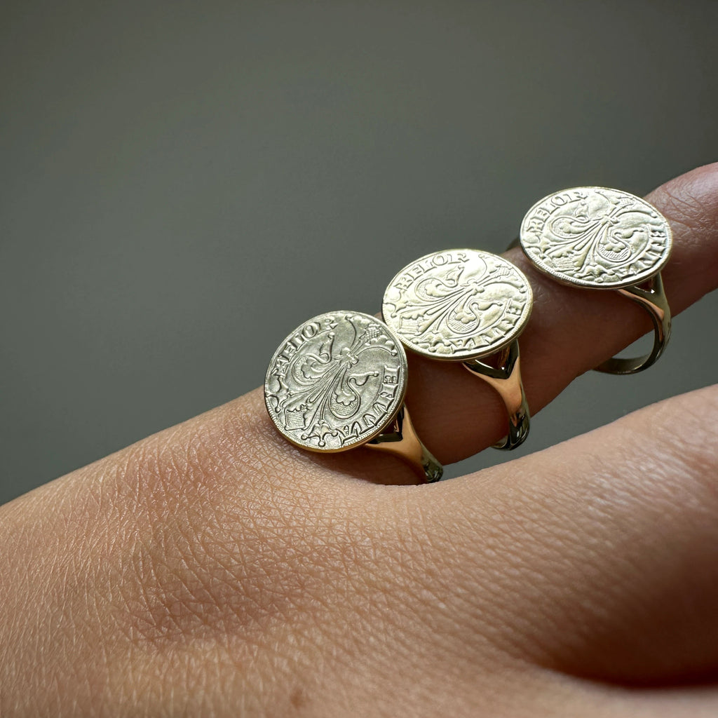 Three 18k gold florin coin rings are worn on a person's fingers