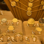 18k Italian Gold Florin Coin rings displayed on the jewelry stand of the famous Ponte Vecchio, Florence. With matching gold coin necklaces hanging behind them.
