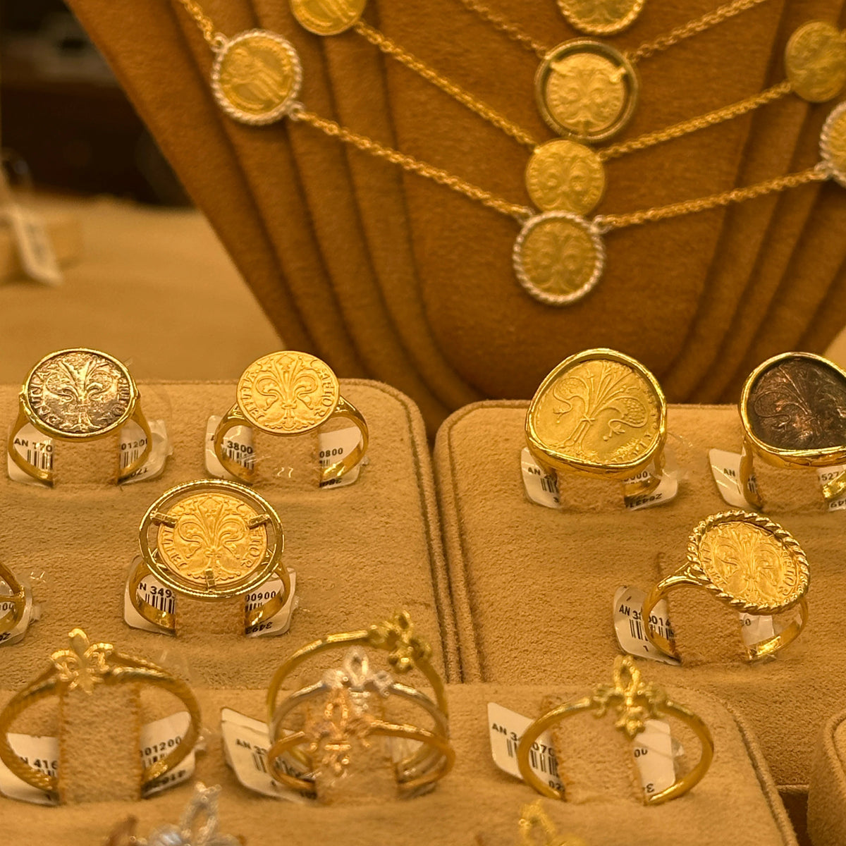 18k Italian Gold Florin Coin rings displayed on the jewelry stand of the famous Ponte Vecchio, Florence. With matching gold coin necklaces hanging behind them.