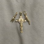 Three 18k Italian gold pendants. Crucifix,  Italian Hand & Italian Horn, arranged on a textured gray fabric background.