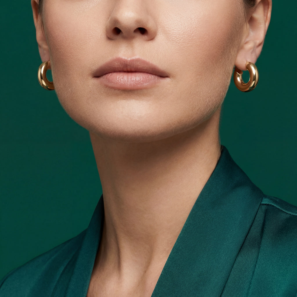 Close-up of woman wearing 18k gold bold dome hoop earrings