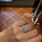 A close-up of a hand wearing a three-band diamond ring set in 18k white and yellow gold.